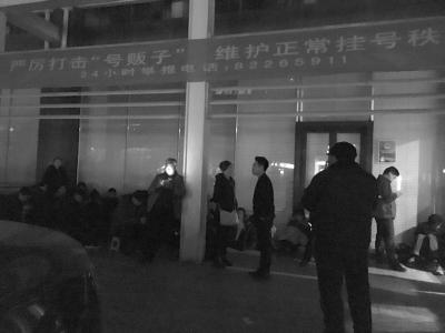 门诊大楼左侧特需挂号处有十几名号贩子在排队，上方挂着“打击号贩子”的横幅。